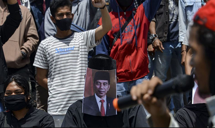 Students cover their faces with Indonesian President Joko Widodo during a demonstration